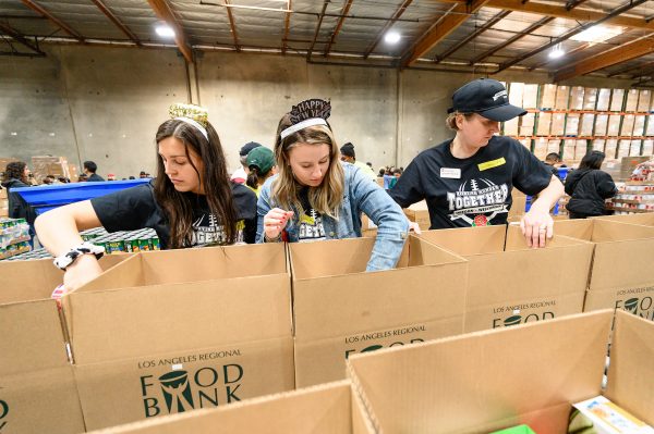 UW students Olivia Haessly (left) and Caitlyn Raatz (center) work with Dean of Students Christina Olstad (right) to fill boxes with canned goods.